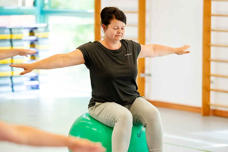 Balanceübung mit Pezziball in der Sporthalle Balanceübung mit Pezziball in der Sporthalle